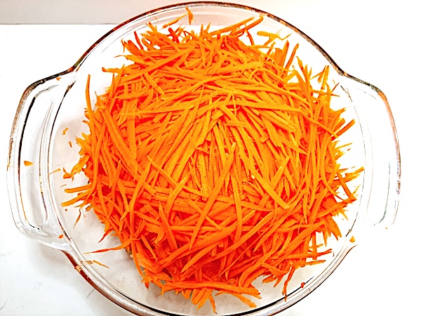 clear glass dish with strips of carrots in it on a white background